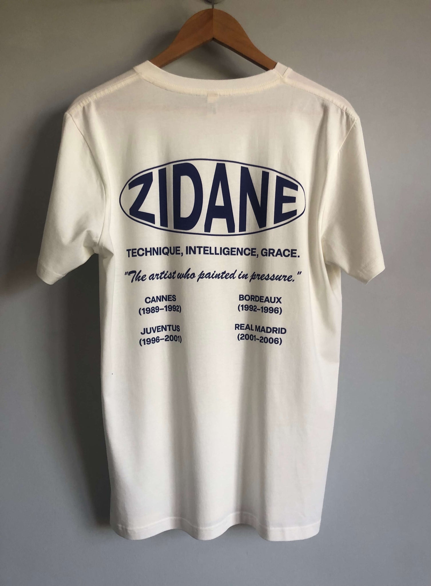 Back view of the Zidane Essentials Tee showcasing a printed timeline and the quote: “The artist who painted in pressure.”
