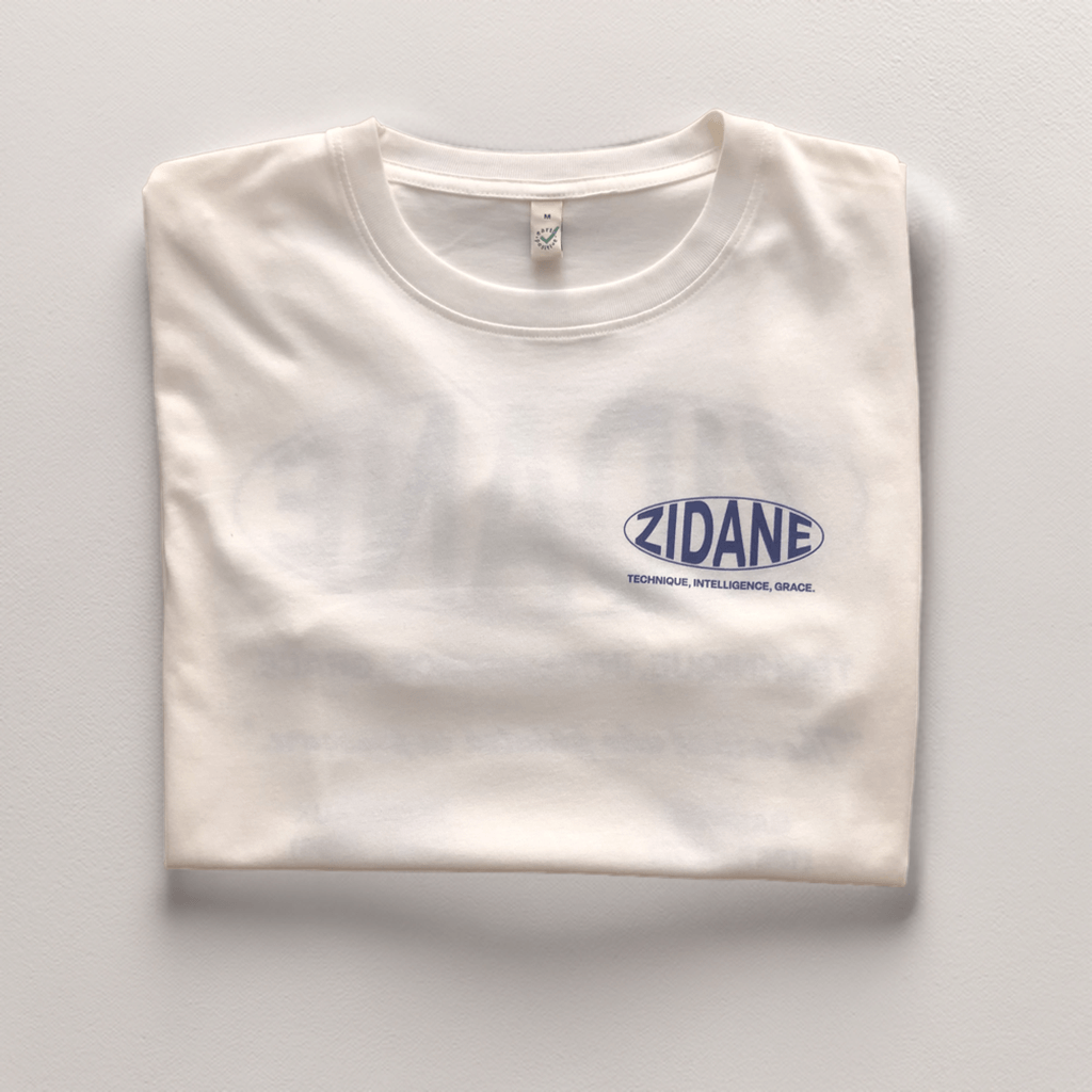 Front view of the off-white Zidane Essentials Tee featuring bold navy typography.