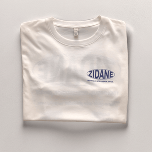 Front view of the off-white Zidane Essentials Tee featuring bold navy typography.