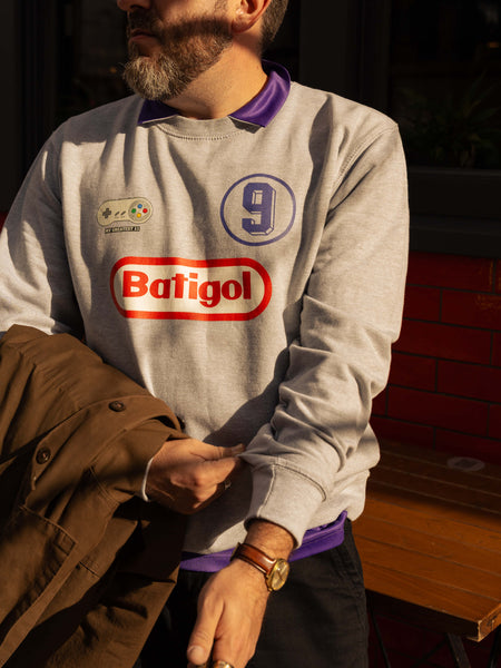 Person wearing a gray sweatshirt with 'Batigol' branding and a number '9'.